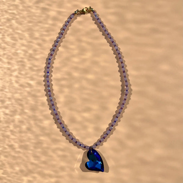Collier avec un pendentif en verre bleu profond, et une alternance de perles parme et perles de rocaille violettes upcyclées