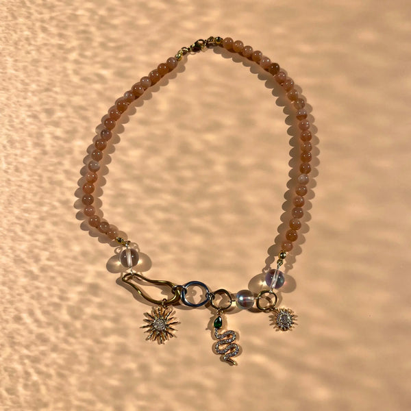 Collier en perles de soleil et trois charms : deux soleils et un serpent, montés sur des formes organiques en acier inoxydable