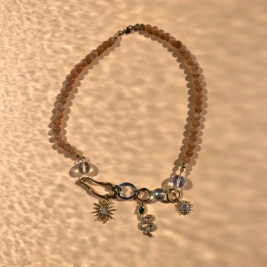 Collier en perles de soleil et trois charms : deux soleils et un serpent, montés sur des formes organiques en acier inoxydable