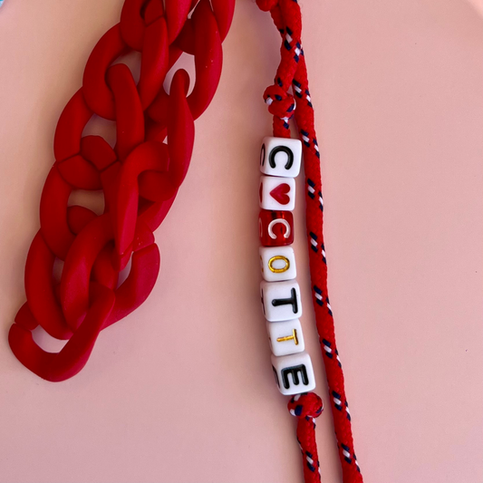 zoom grigri de sac rouge, message en perles "cocotte" avec un coeur à la place d'un des O