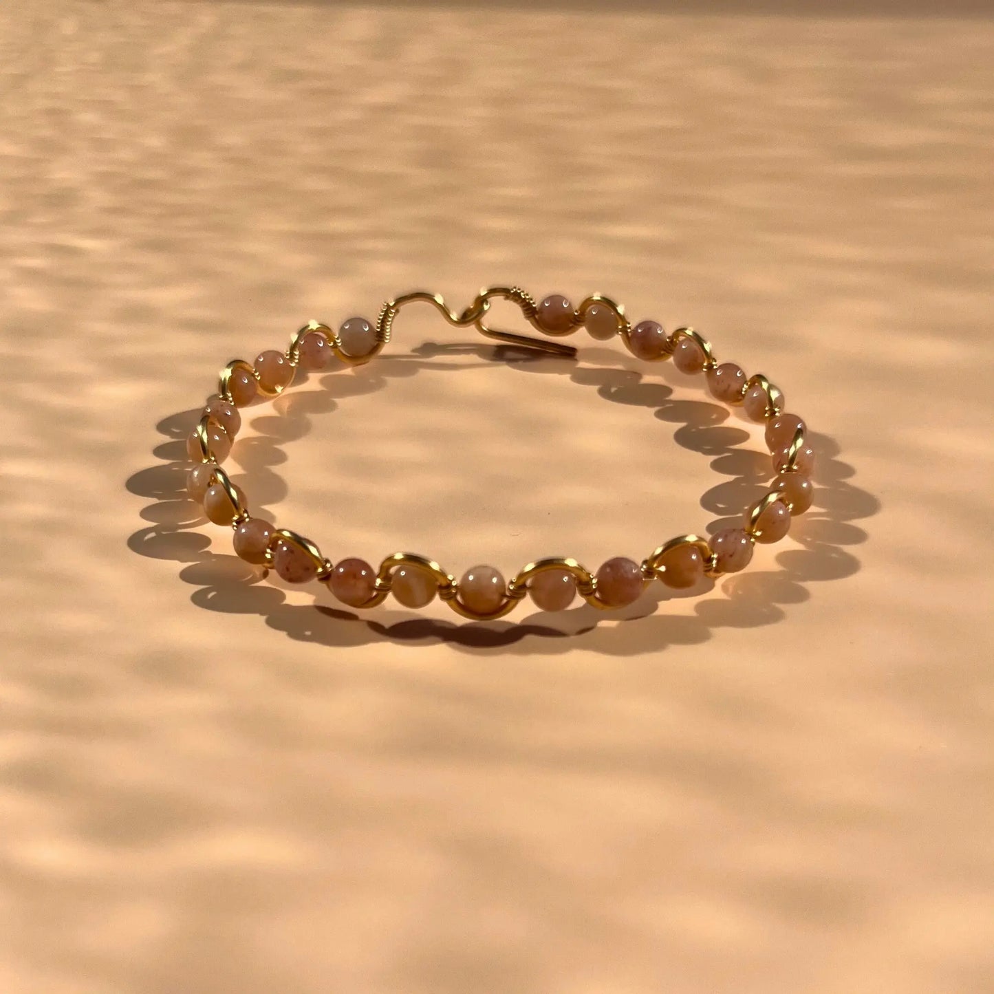 Bracelet en pierre de soleil fait main sur un fil rigide doré