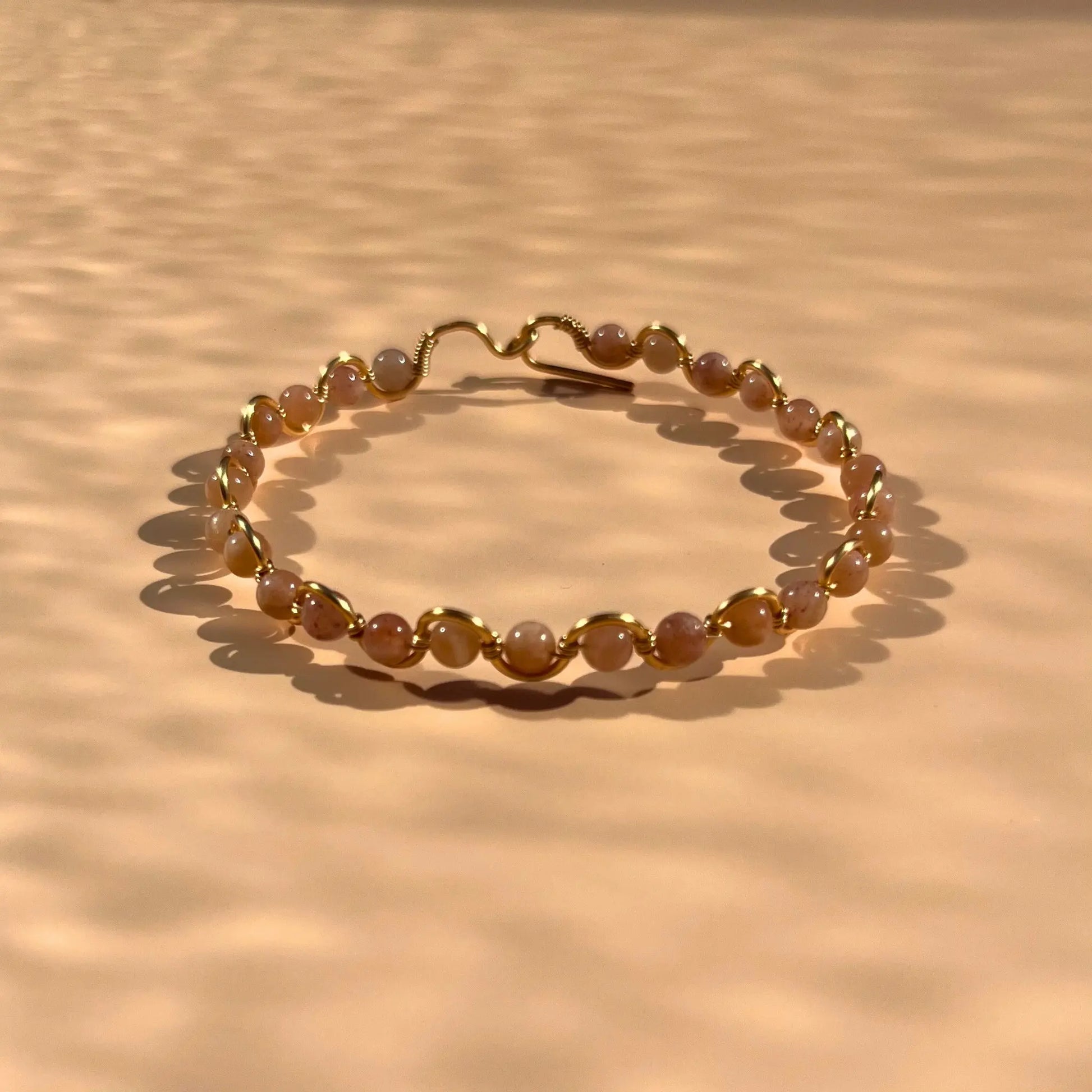 Bracelet en pierre de soleil fait main sur un fil rigide doré