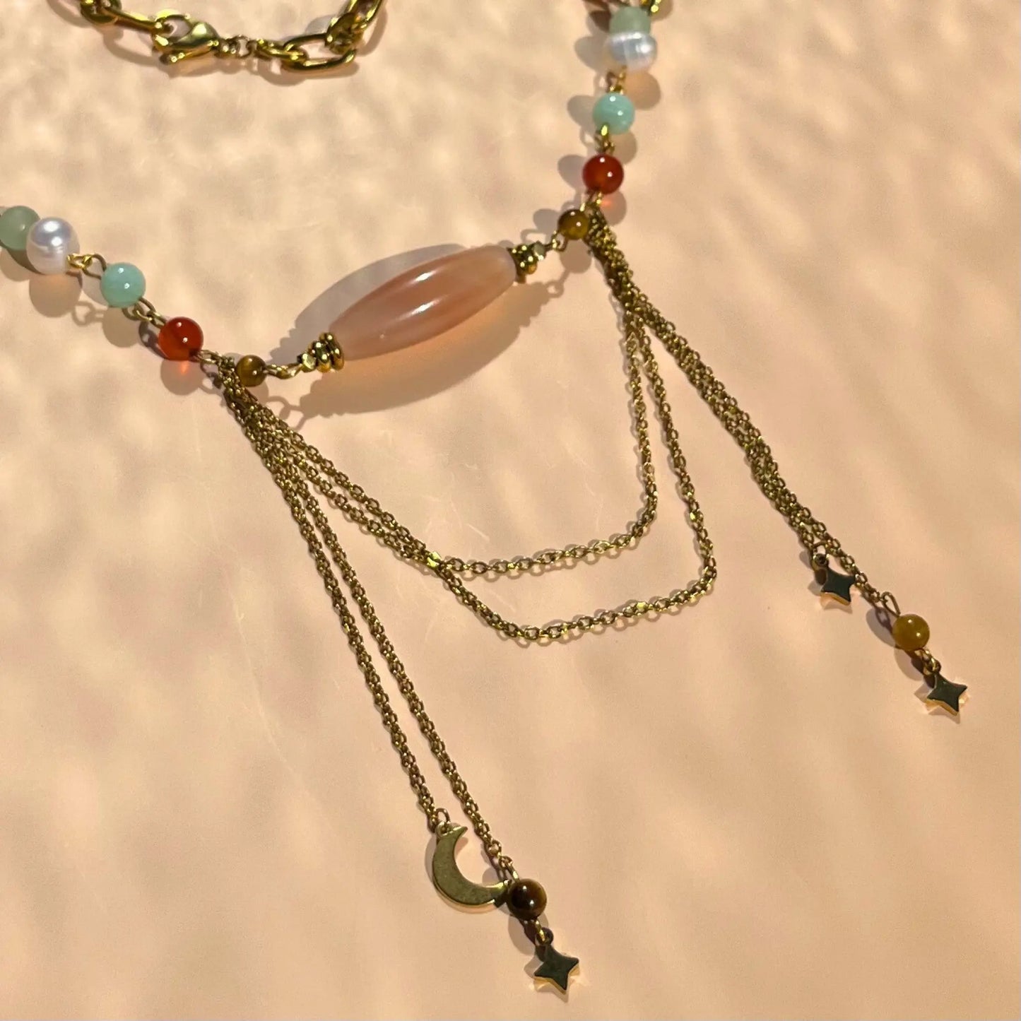 zoom sur le centre du collier en cornaline et amazonite, avec 4 charms pendus à des chaines en acier inoxydable encadrant une agate