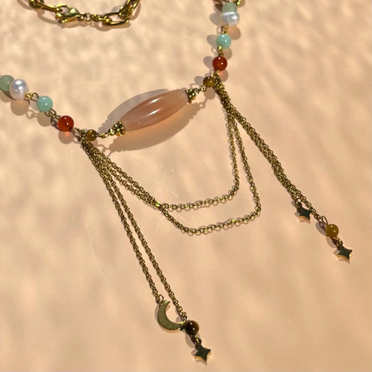zoom sur le centre du collier en cornaline et amazonite, avec 4 charms pendus à des chaines en acier inoxydable encadrant une agate