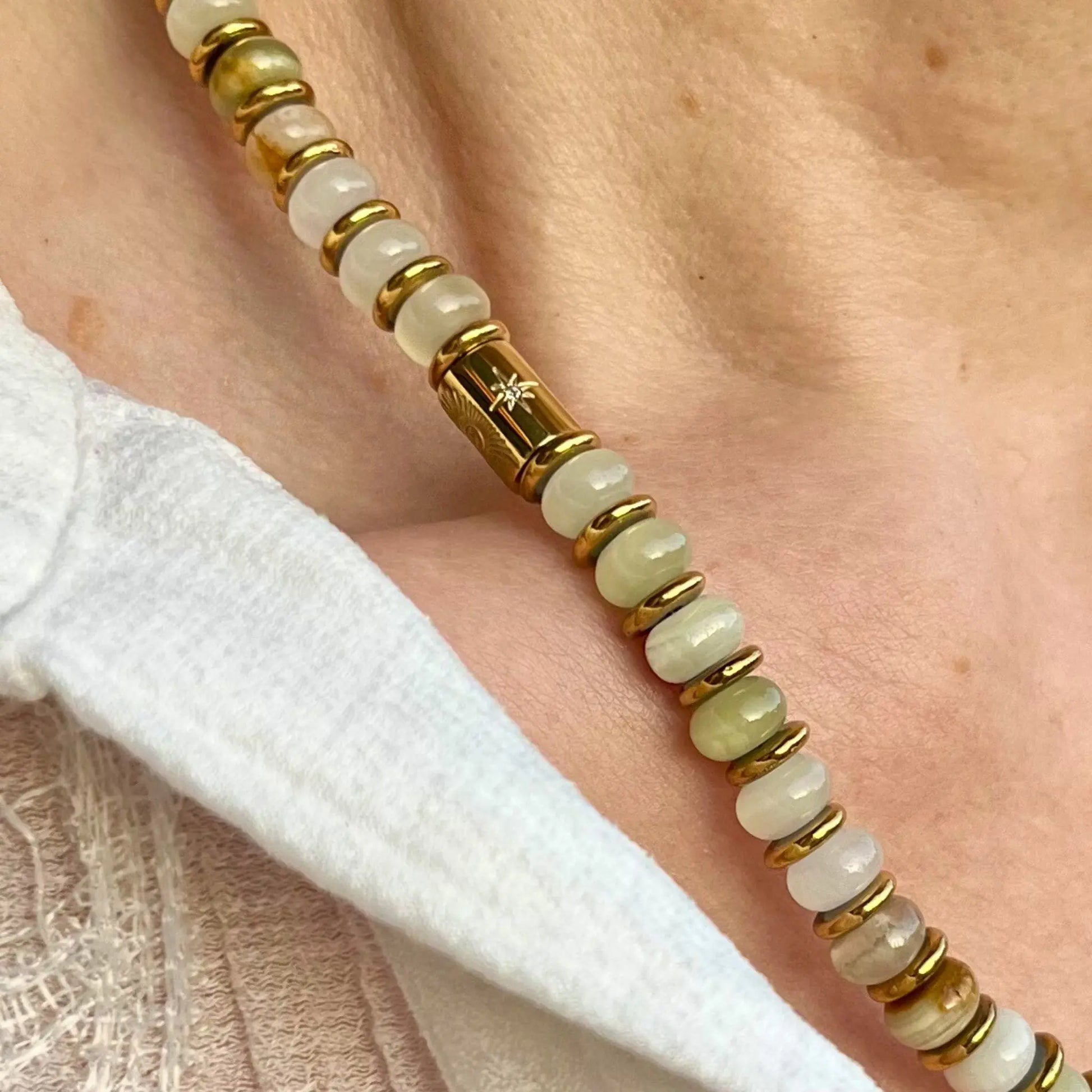 collier en disque de jade et d'hématite, zoom sur le détail de la perle tube plaquée or avec oeil protecteur gravé